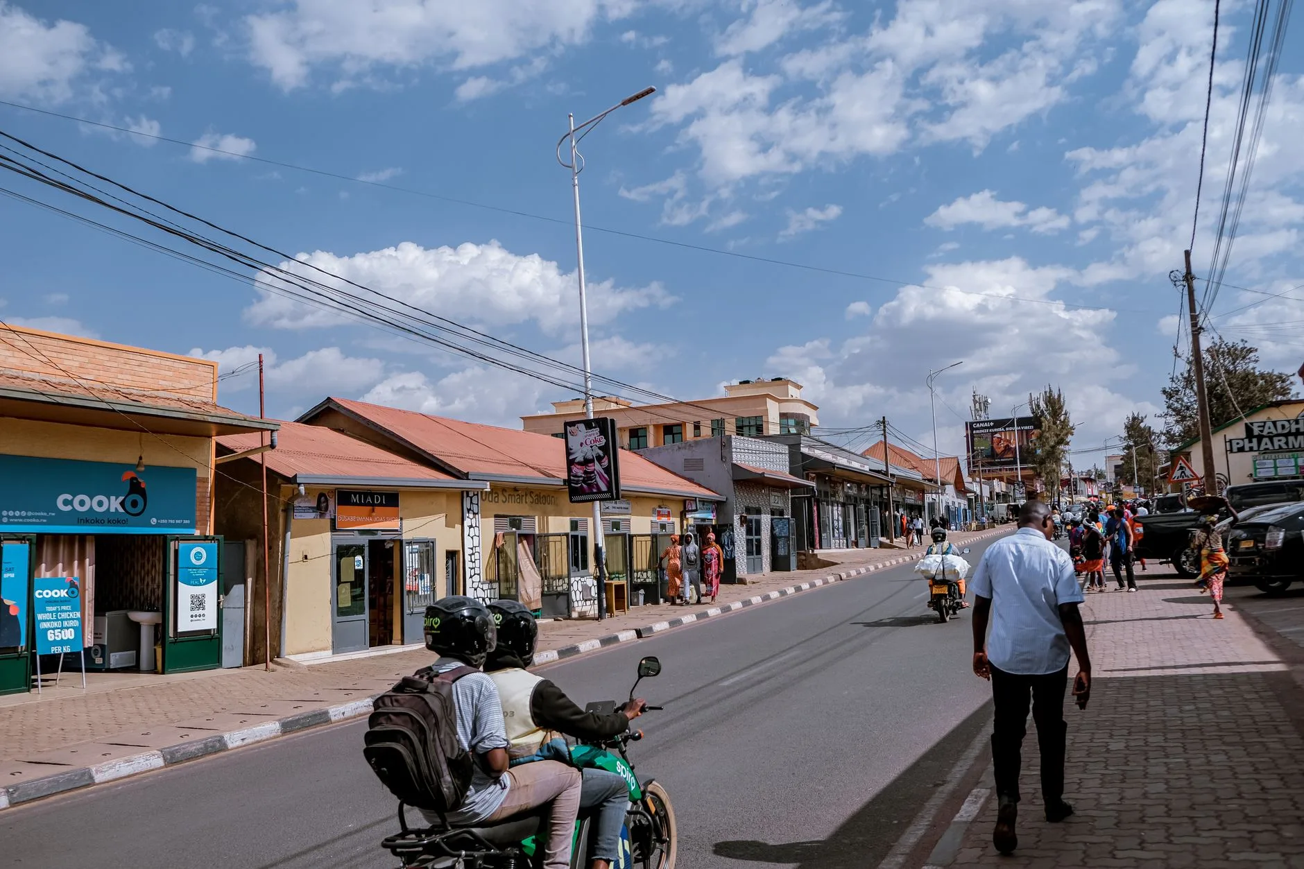 Ruelle animée du quartier de Nyamirambo à Kigali avec boutiques colorées et passants